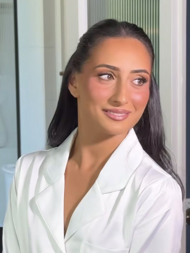 Rayya smiling on her wedding morning, in a white satin robe