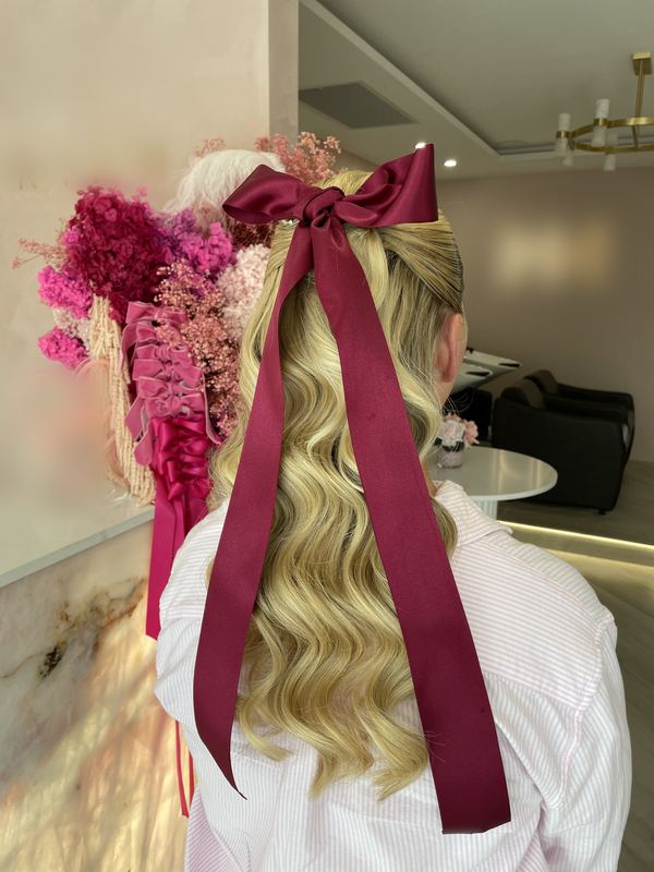 Blonde half up waves tied with a long burgundy satin ribbon