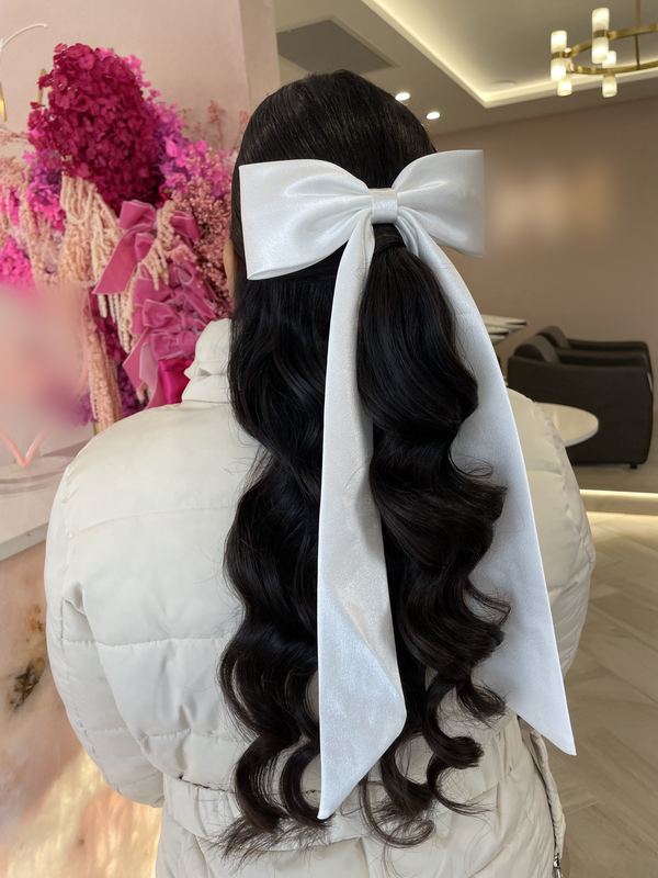 Long glossy waves finished with an oversized white satin bow